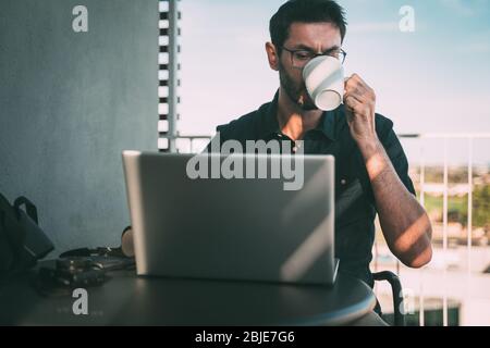 man teleworking at home or traveling and drinking coffee. Stock Photo