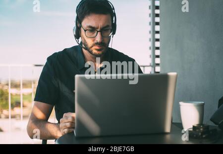 Man with headphones teleworking at home or traveling Stock Photo