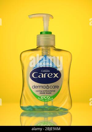 Carex refillable bottle antibacterial hand wash empty with a small amount left isolated on a yellow background with a reflection. Stock Photo