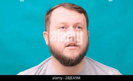 Portrait of an angry swearing bearded man on a blue background. Stock Photo