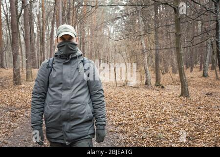 One man with a covered face walking through the autumn forest Stock Photo