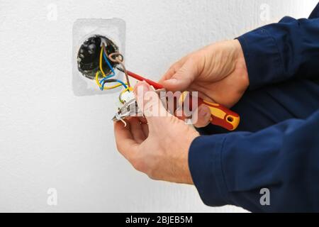 Electrician disassembling wall socket in new building, closeup Stock Photo