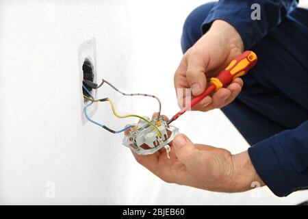 Electrician disassembling wall socket in new building, closeup Stock Photo