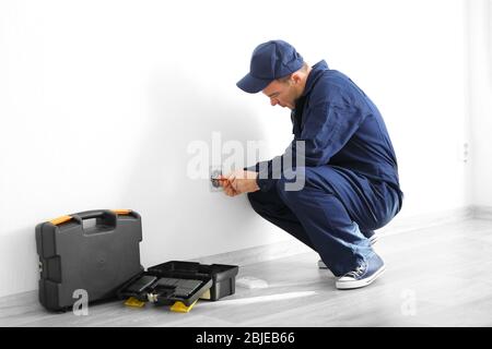 Electrician disassembling wall socket in new building Stock Photo