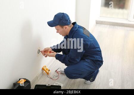 Electrician measuring voltage of socket in new building Stock Photo