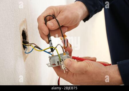 Electrician attaching wires to socket in new building, closeup Stock Photo