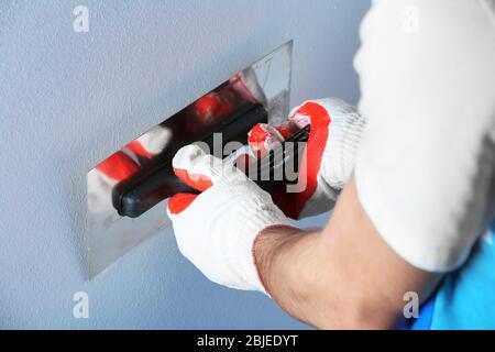 Builder using plastering tool for finishing wall Stock Photo