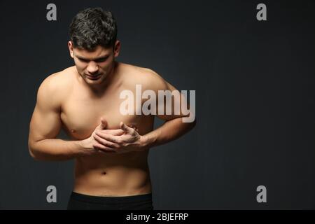 Handsome man having heart attack on dark background Stock Photo