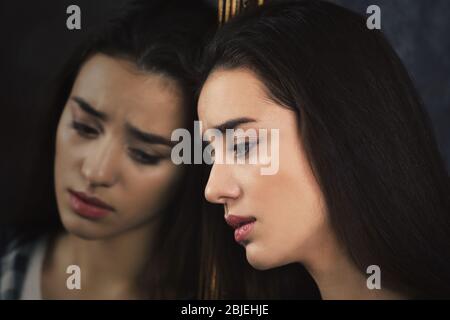 Depressed young woman and her reflection in mirror Stock Photo
