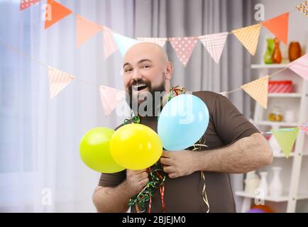 Funny fat man celebrating birthday at home Stock Photo