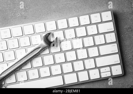 Modern wireless keyboard and spanner on gray background Stock Photo