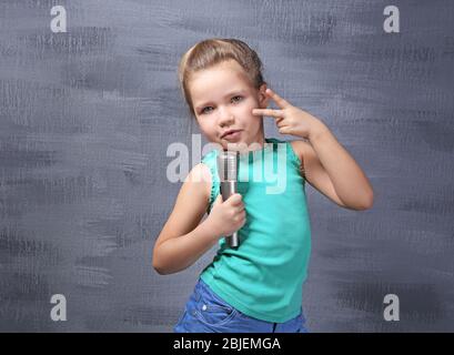 Cute little girl with microphone on color background Stock Photo