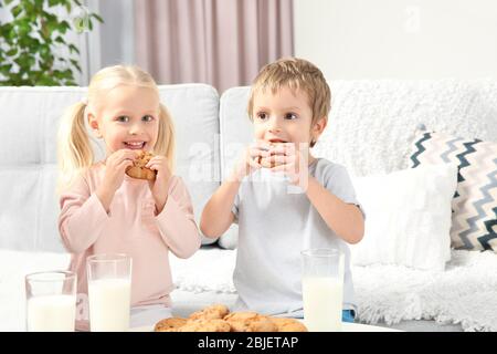 Little kids eating cookies at home Stock Photo