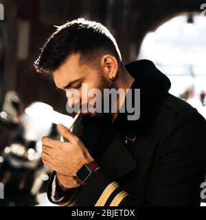 Young and attractive man with elegant outfit lighting a cigarette Stock Photo