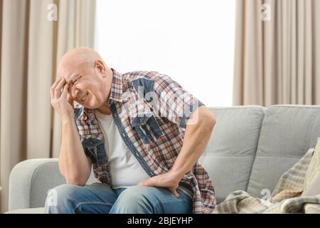 Senior man suffering from headache at home Stock Photo