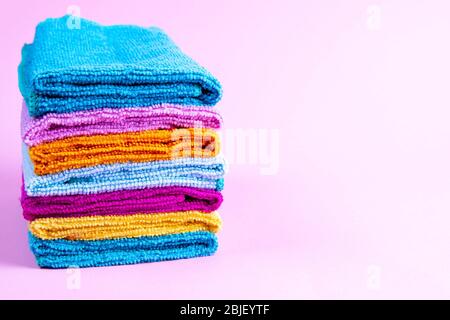 Multi-colored towels on a pink background. Pink, beige, yellow, orange and blue towels. Place for writing. House order. Stock Photo