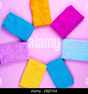Multi-colored towels laid out in the form of the sun on a pink background. Pink, beige, yellow, orange and blue towels. Place for writing. House order Stock Photo