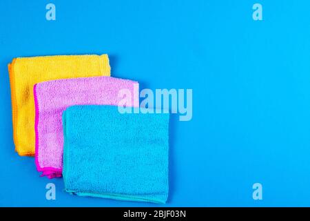 Multi-colored towels on a blue background. Pink, beige, yellow and blue flower towels. Place for writing. House order Stock Photo