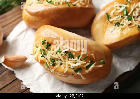 Tasty buns with garlic, cheese and herbs on paper Stock Photo