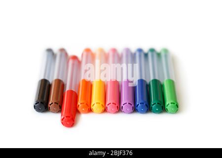 Close-up of set of colorful rainbow colored marker pens in a row, low angle view. Red marker is apart, concept of standing out. Isolated on white. Stock Photo