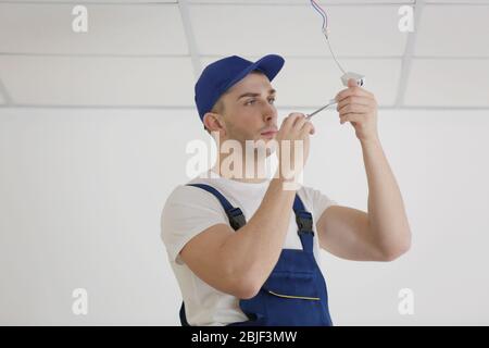 Electrician repairing ceiling light Stock Photo