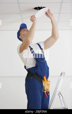 Electrician repairing ceiling light Stock Photo