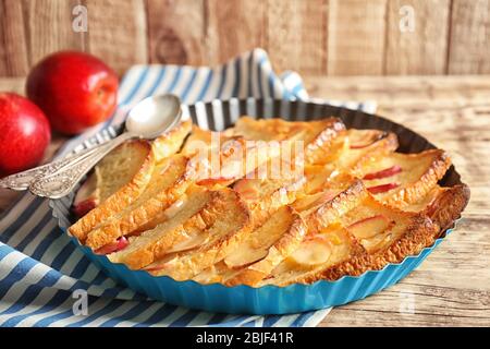 Tasty bread pudding with apples in baking dish on kitchen table Stock Photo