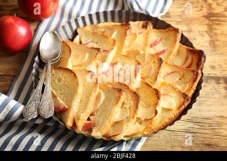 Tasty bread pudding with apples in baking dish on kitchen table Stock Photo
