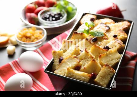 Delicious bread pudding with currant in baking dish on kitchen table Stock Photo