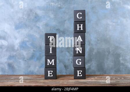 Cubes with text TIME CHANGE on table against color wall Stock Photo
