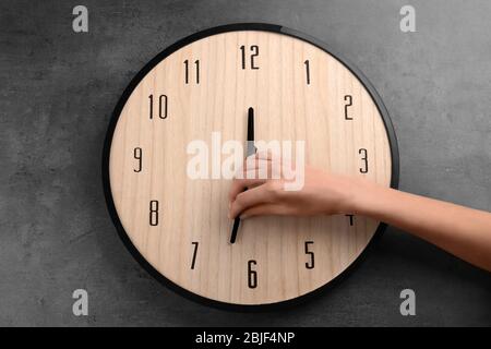 Female hand change time on big wall clock Stock Photo