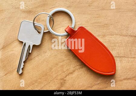 Key with red blank leather tag or label on wooden background. Buying a new house, real estate or mortgage concept. Flat lay image with copy space. Stock Photo