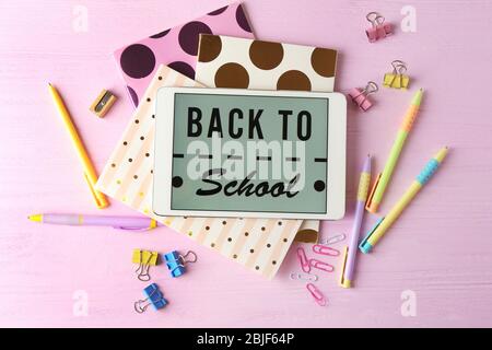 Tablet with BACK TO SCHOOL message and stationery on pink wooden background Stock Photo