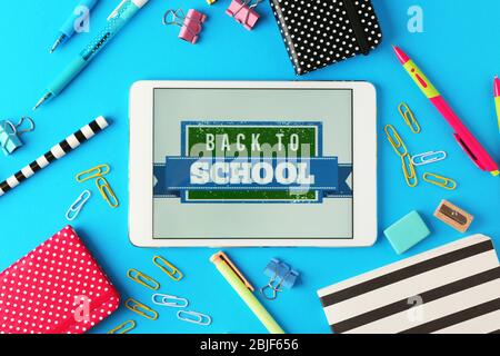 Tablet with BACK TO SCHOOL message and stationery on blue background Stock Photo