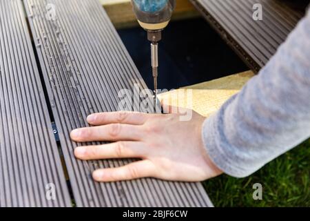 terrace deck construction - man installing wpc composite decking boards Stock Photo
