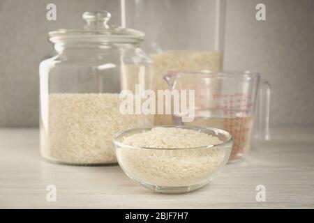 Kitchen ware with rice and water on wooden table Stock Photo