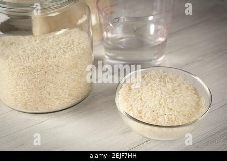 Kitchen ware with rice and water on wooden table Stock Photo