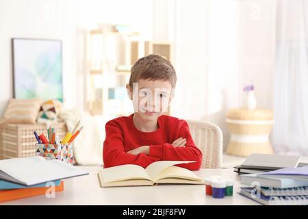 Schoolboy doing homework at table in room Stock Photo