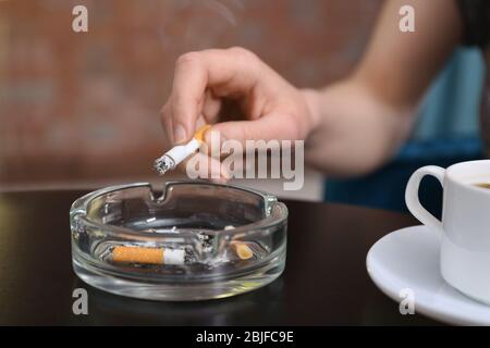 Smoking woman's hand holding cigarette sitting at table Stock Photo