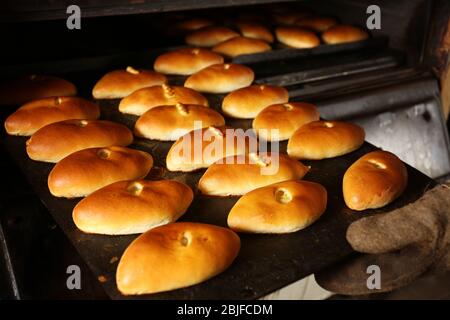 Female hand holding baking tray with buns Stock Photo
