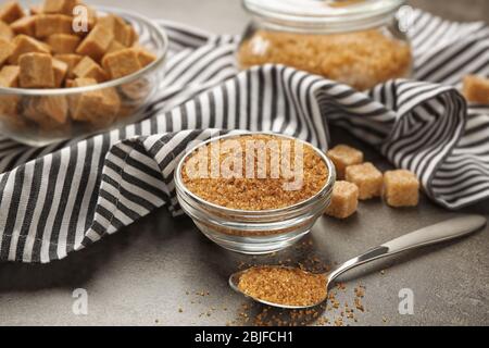 Brown sugar in dishware on gray background Stock Photo