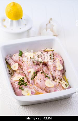 Marinated rabbit legs with lemon, garlic and herbs in the casserole Stock Photo