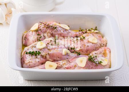 Marinated rabbit legs with lemon, garlic and herbs in the casserole Stock Photo