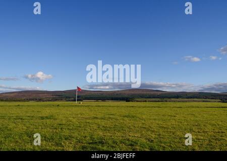 A red flag stands in a field, the site of the Battle of Culloden (1746) near Inverness in Scotland, UK Stock Photo