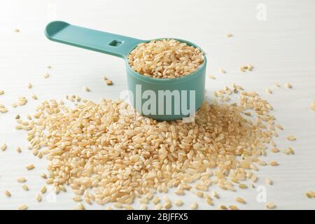 Measure scoop full of brown rice on white background Stock Photo - Alamy
