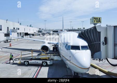 LOS ANGELES, CA -26 APR 2020- An airplane from United Airlines (UA) and a baggage handler wearing a face mask during the COVID-19 crisis at the Los An Stock Photo