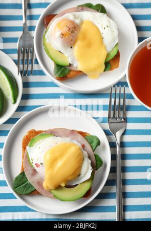 Plates with tasty eggs Benedict on table Stock Photo