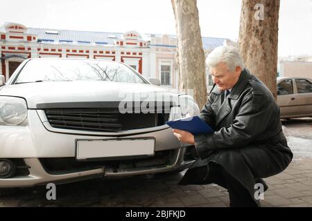Loss adjuster inspecting car after accident Stock Photo