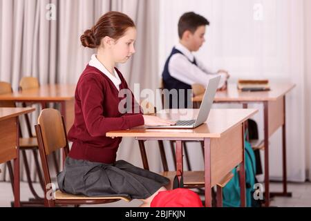 Incorrect posture concept. Pupils sitting at desk in classroom Stock Photo