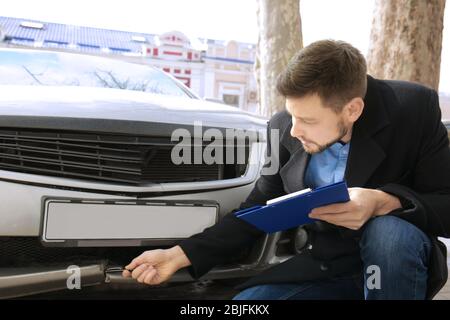 Loss adjuster inspecting car after accident Stock Photo